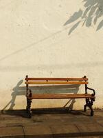 Old wooden bench in front of old dirty white wall. Retro vintage concept background image. Oldies but goodies photo