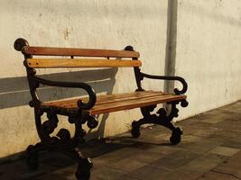 Old wooden bench in front of old dirty white wall. Retro vintage concept background image. Oldies but goodies photo