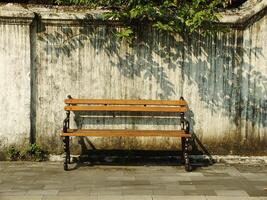 Old wooden bench in front of old dirty white wall. Retro vintage concept background image. Oldies but goodies photo
