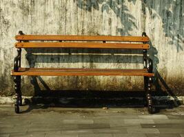 Old wooden bench in front of old dirty white wall. Retro vintage concept background image. Oldies but goodies photo