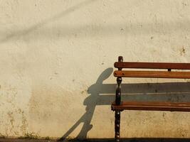 Old wooden bench in front of old dirty white wall. Retro vintage concept background image. Oldies but goodies photo