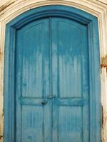 ancient and antique blue wooden javanese door with cracking old wall around it photo