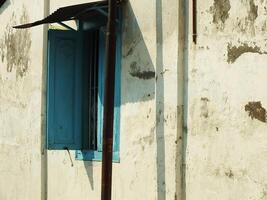 ancient and antique blue wooden window with cracking old wall around it photo