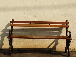 Old wooden bench in front of old dirty white wall. Retro vintage concept background image. Oldies but goodies photo