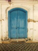 ancient and antique blue wooden javanese door with cracking old wall around it photo