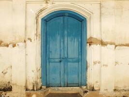 ancient and antique blue wooden javanese door with cracking old wall around it photo