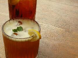 Cold brew fresh iced tea with lemon on wooden table. Refreshing drink on a hot summer day. Cafe image concept design background photo