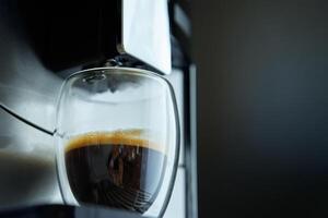 Coffee Machine Prepares Fresh Espresso in Clear Glass Against Dark Background photo