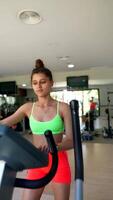 Young woman engaging in a workout session on an elliptical machine in a contemporary gym setting video