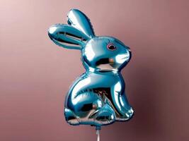 A blue foil balloon shaped like a bunny against a pink background photo