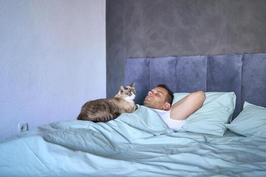 un joven hombre dormido con un gato en su pecho, Mañana rutina foto