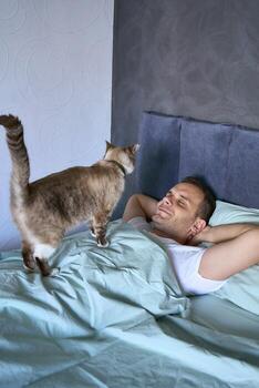 un joven hombre dormido con un gato en su pecho, Mañana rutina foto