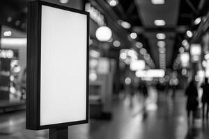 A monochrome image showing an empty advertisement board in a busy shopping mall photo