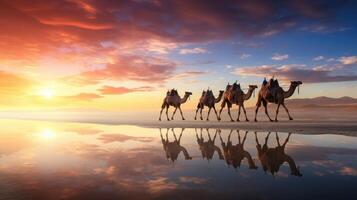 Silhouette of a camel caravan walking along a beach at sunset, with reflection on water photo