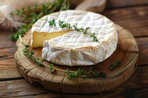 Camembert cheese with fresh thyme on wood photo