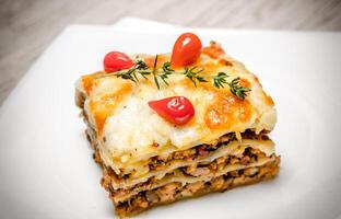 Portion of lasagna on the wooden table photo
