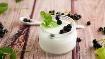 homemade sweet yogurt in a jar with black currants, on a wooden table video