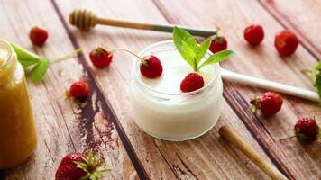 homemade sweet yogurt in a jar with strawberries, on a wooden table video