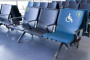Rows of empty blue seats in public waiting area for people with physical disabilities and people with special needs, charging phone photo