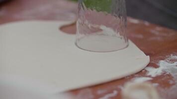 The chef cuts out a dumpling shape in the dough using a glass video