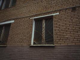 several gloomy windows with bars on a brick house. looked like a prison photo