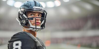 American football player in a black helmet and uniform stands and looks away. Against the background of the arena stands and floodlights. Copy space photo