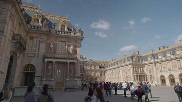 Versailles, France - March 19, 2024 - Tourists crowd the Royal Court at the Palace of Versailles with the palace's architecture and details as a background video