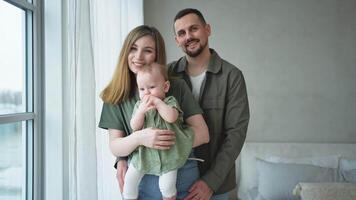 Happy family at home. Mother father holding little toddler child. Mom dad baby girl relax playing having fun together. Woman man hugging embracing baby with love care. Parent of breast feeding baby video