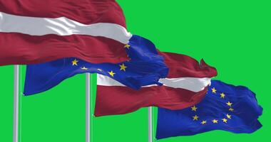 Flags of Latvia and the European Union waving isolated on green background video