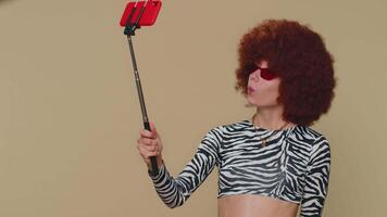 Woman traveler blogger taking selfie on mobile phone selfie stick, communicating call online video