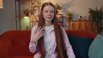 Close-up of happy beautiful young redhead child girl smiling looking at camera at home on couch video
