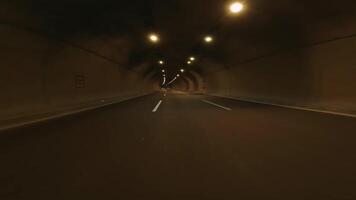 First person view as car drives through tunnel in mountains. The highlights the underground tunnel's structure and lighting. Experience the contrast of light and shadow within the tunnel video