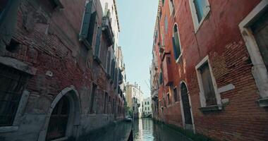 View from a gondola floating on the canals of Venice, Italy. The bow of the boat that sails into the romantic cityscape surrounded by the architecture of beautiful houses. High quality 4k footage video