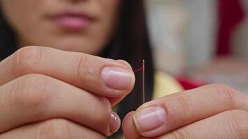 sömmerska med syn problem är oförmögen till tråd en tunn röd tråd genom de öga av en nål. stänga upp. långsam rörelse. 4k video