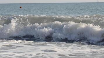 Waves with white foam on the seashore where people rest. CREATIVE. A small storm in windy weather on the beach video