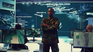 Portrait of national guard commander dressed in military camouflage uniform, team leader overseeing operations in control center. Army officer works on missions at federal agency base. Camera B. video