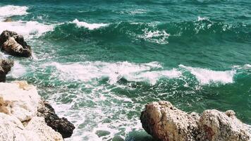 Serene Waters Dance. Turquoise Waves Meet Natures Stone Experience the beauty of turquoise sea waves crashing on majestic rocks while surrounded by the calming sounds of nature. video
