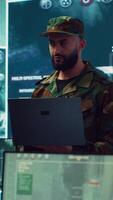 Vertical Special operations soldier allocating resources to different units based on mission needs, examines strategic data on a big screen in military control center. Marine corps troops. Camera A. video