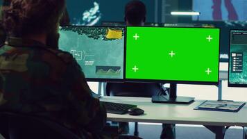 Team of IT military specialists working with a greenscreen on a big display, searching for real time data via reconnaissance CCTV system. Soldiers in power base transmitting information. Camera A. video