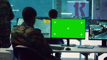 Intelligence analyst reviews ships activity next to an isolated mockup screen, following gps coordinates of vessels anchoring along the coastal ports. Army officer in monitoring room. Camera A. video