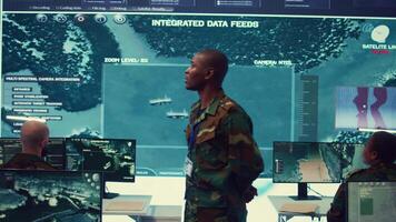 Major general updating and maintain the command center databases with current operational data, monitoring surveillance radar footage to ensure national safety. Control room. Camera B. video