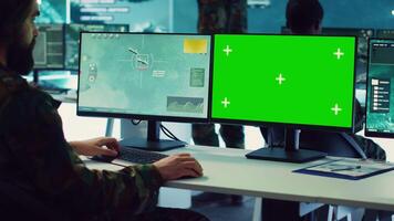Army officer uses satellite radar footage and a greenscreen in military command post, working to gather intelligence and detect enemy ships. Commander operator at government agency. Camera A. video