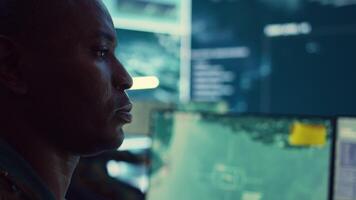 Lieutenant colonel gathering intelligence from federal radar systems, working with his crew in military command control room. Examining satellite imagery for reconnaissance mission. Camera B. video