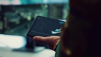 Navy operations specialist following hostile warship trajectory around the national waters, working on ensuring protection via satellite radar system on a tablet. IT professional. Close up. Camera A. video