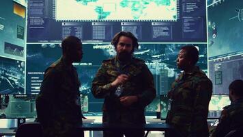 Brigadier general and his staff studying radar data on a holographic image, working with artificial intelligence and holography in a military base of operations. Ensure national safety. Camera B. video