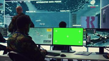 Private monitors national guard activity with military CCTV satellite system, working with a greenscreen display on pc in command center. IT reconnaissance operator tracking ships. Camera B. video