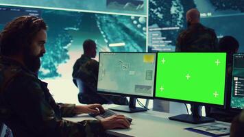 Army officer uses satellite radar footage and a greenscreen in military command post, working to gather intelligence and detect enemy ships. Commander operator at government agency. Camera B. video