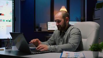 Exhausted businessman working overtime at financial company deadline project. Workaholic executive manager in startup business office yawning while typing economic strategy on laptop in evening video