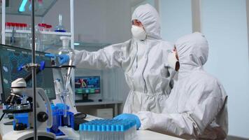 Scientist team in prorection suit arguing in front of pc looking at virus development in equipped laboratory.Team of scientists analysing vaccine evolution using high tech for researching treatment video