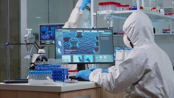 Medical scientist in ppe suit working with DNA scan image typing on pc in equipped laboratory. Examining vaccine evolution using high tech and chemistry tools for scientific research virus development video